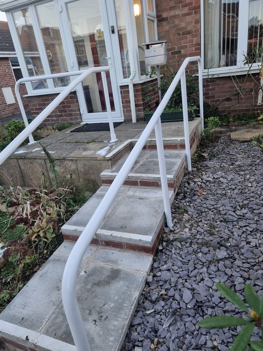Metal handrail fitted along concrete steps and ramp